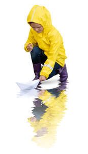 cut out little girl in a yellow raincoat floating a paper boat