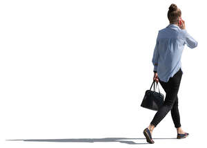 backlit woman walking and talking on the phone