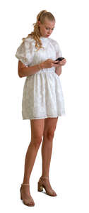 cut out woman in a short white dress standing with a phone in her hand