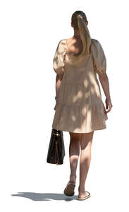 cut out young woman in a summer dress walking in a tree shade