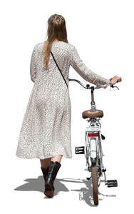 cut out woman in a long summer dress walking and pushing a bike