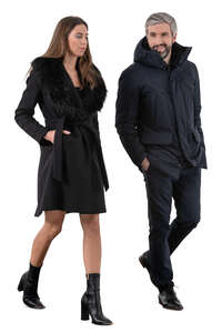 cut out man and woman wearing black overcoats walking