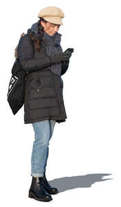 woman in a winter overcoat standing and texting