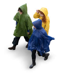 three cut out women in raincoats walking seen from above