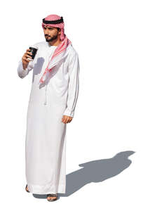 cut ot arab man in traditional emirati clothes standing and drinking coffee