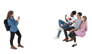 woman taking a picture of her three friends sitting on the bench