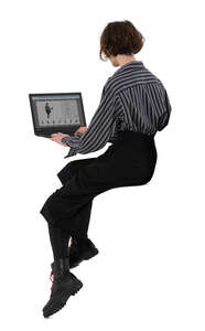 cut out woman sitting on a counter height table with a laptop