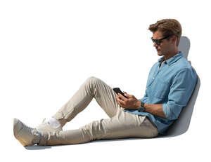 cut out young man sitting outdoors and looking at his phone