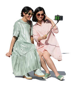 two cut out young asian women sitting and taking a selfie