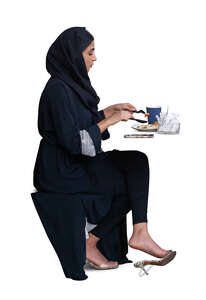 cut out muslim woman sitting in a cafe and eating