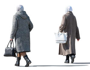 two sidelit older women in overcoats walking