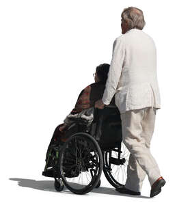 elderly man pushing a woman in a wheelchair