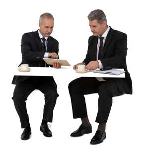 two cut out businessmen drinking coffee and discussing business