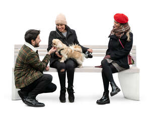 cut out man talking to two women sitting with a dog
