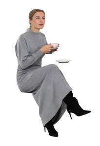 cut out woman in a grey dress drinking coffee in a cafe