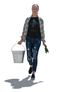 cut out backlit woman working in a garden walking and carrying a bucket