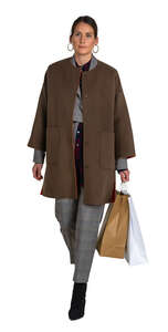 cut out woman in a brown overcoat carrying shopping bags walking