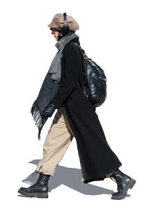 cut out woman with headphones and long black coat walking