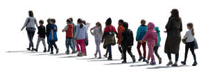 cut out group of backlit schoolkids with their teachers walking