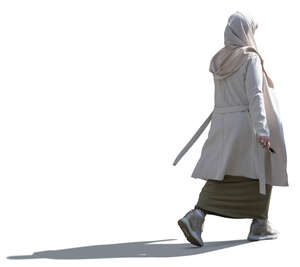 backlit muslim woman with a beige hijab walking