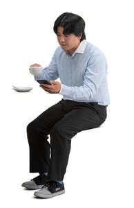 cut out asian man sitting in a cafeteria and drinking coffee