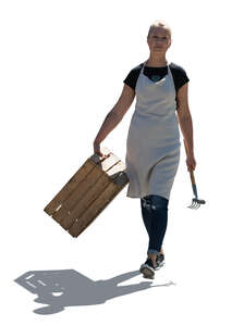 cut out backlit female gardener with a wooden crate walking