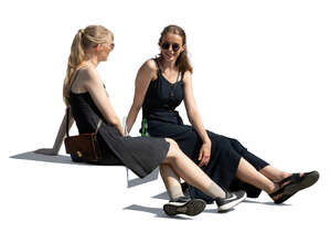 two cut out young women sitting casually and talking