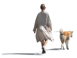 cut out woman in a flowy white jacket walking a dog