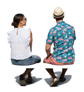 two cut out people sitting outside seen from back angle