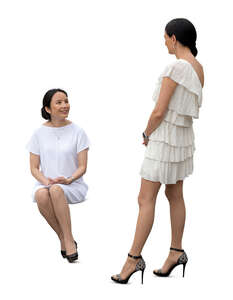 cut out woman sitting and talking to another woman standing next to her