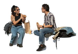 man and woman sitting and eating lunch outside on the street