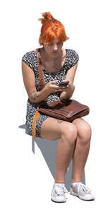 young woman with a phone sitting outside in sunlight