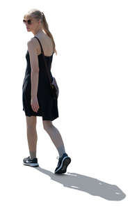 backlit woman in a black summer dress walking