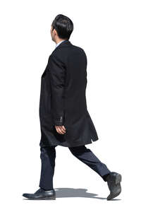 asian businessman wearing a suit and a black overcoat walking