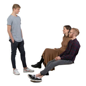 man standing and talking to his two friends sitting in front of him