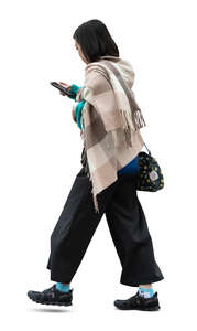 asian woman with a big scarf walking while reading her phone