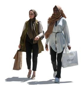two backlit middle eastern women with shopping bags walking