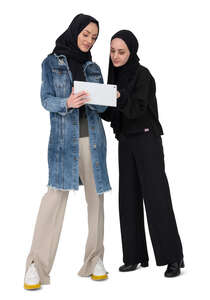 two muslim women wearing hijabs looking at a tablet together