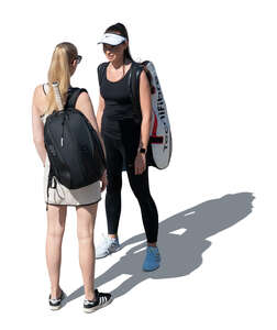 two women with tennis equipment standing and talking seen from higher angle