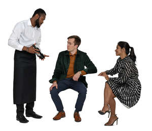 waiter serving wine to two people sitting at a restaurant table