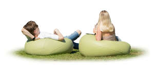 man and woman lying on the bean chairs outside on the grass