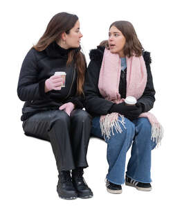 two women in winter sitting and drinking hot coffee