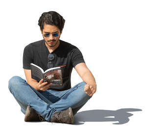 man sitting on the ground outside and reading a book