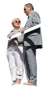 two older people standing up on a balcony and talking