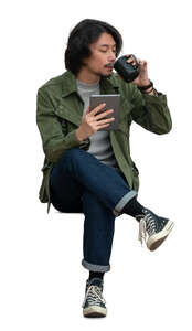 trendy asian man with a tablet sitting and drinking coffee