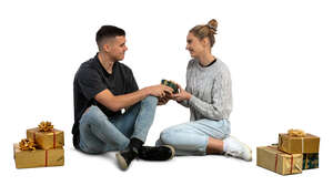 man and woman sitting on the floor and exchanging christmas gifts
