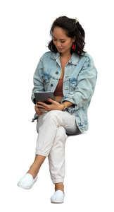 asian woman sitting and reading smth from a tablet