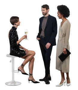 woman sitting and drinking champagne and talking to two friends at a party