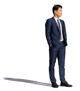 asian man wearing a dark suit standing hands in his pockets