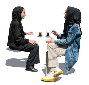 two cut out muslim woman sitting and drinking tea